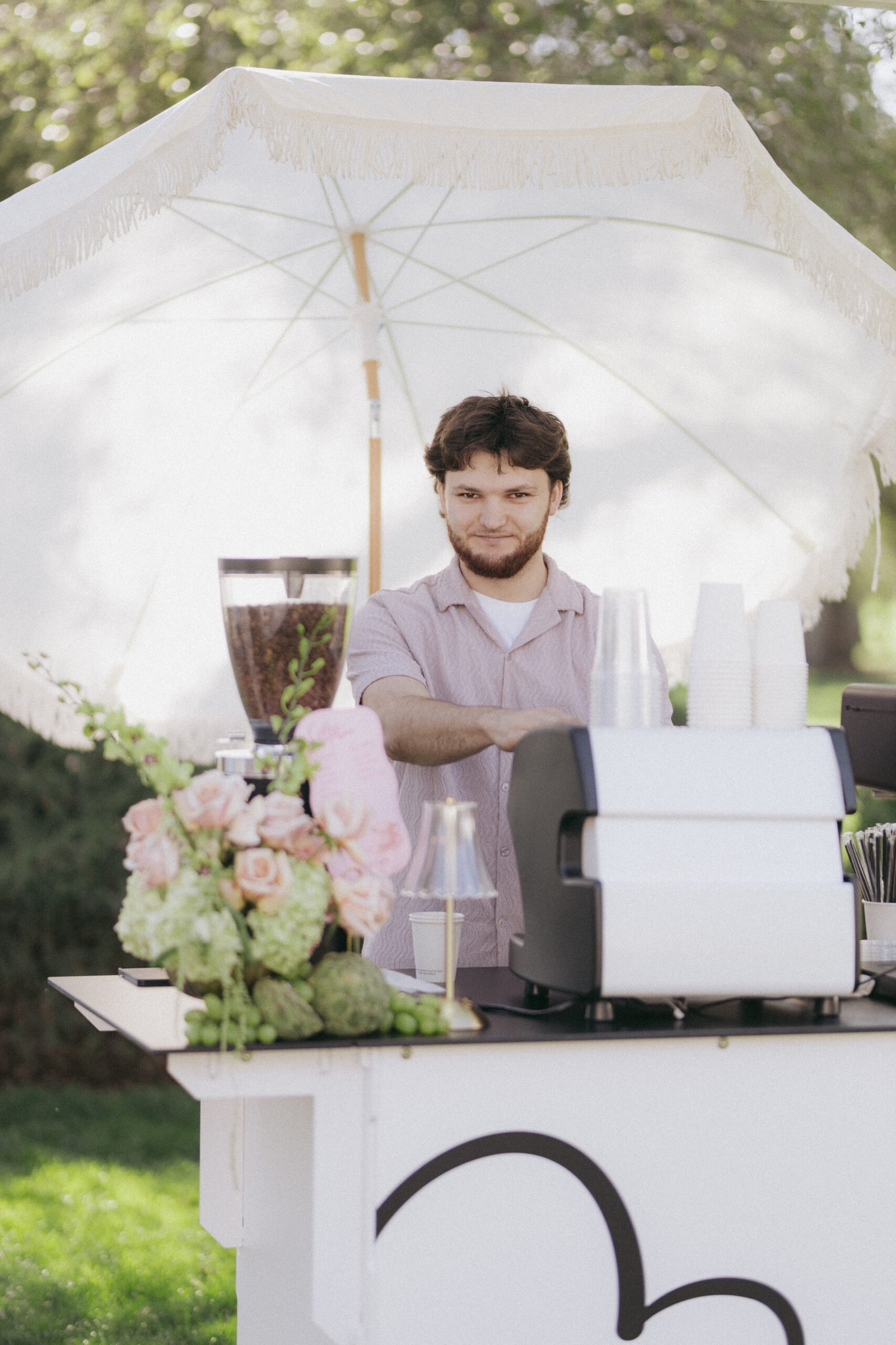 Barista serving coffee under the Holy Coffee umbrella