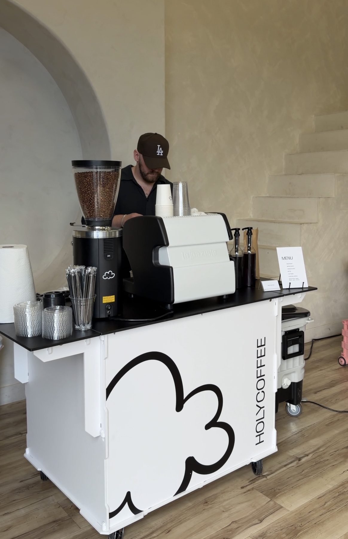 Barista serving from the Holy Coffee cart in a bright white interior