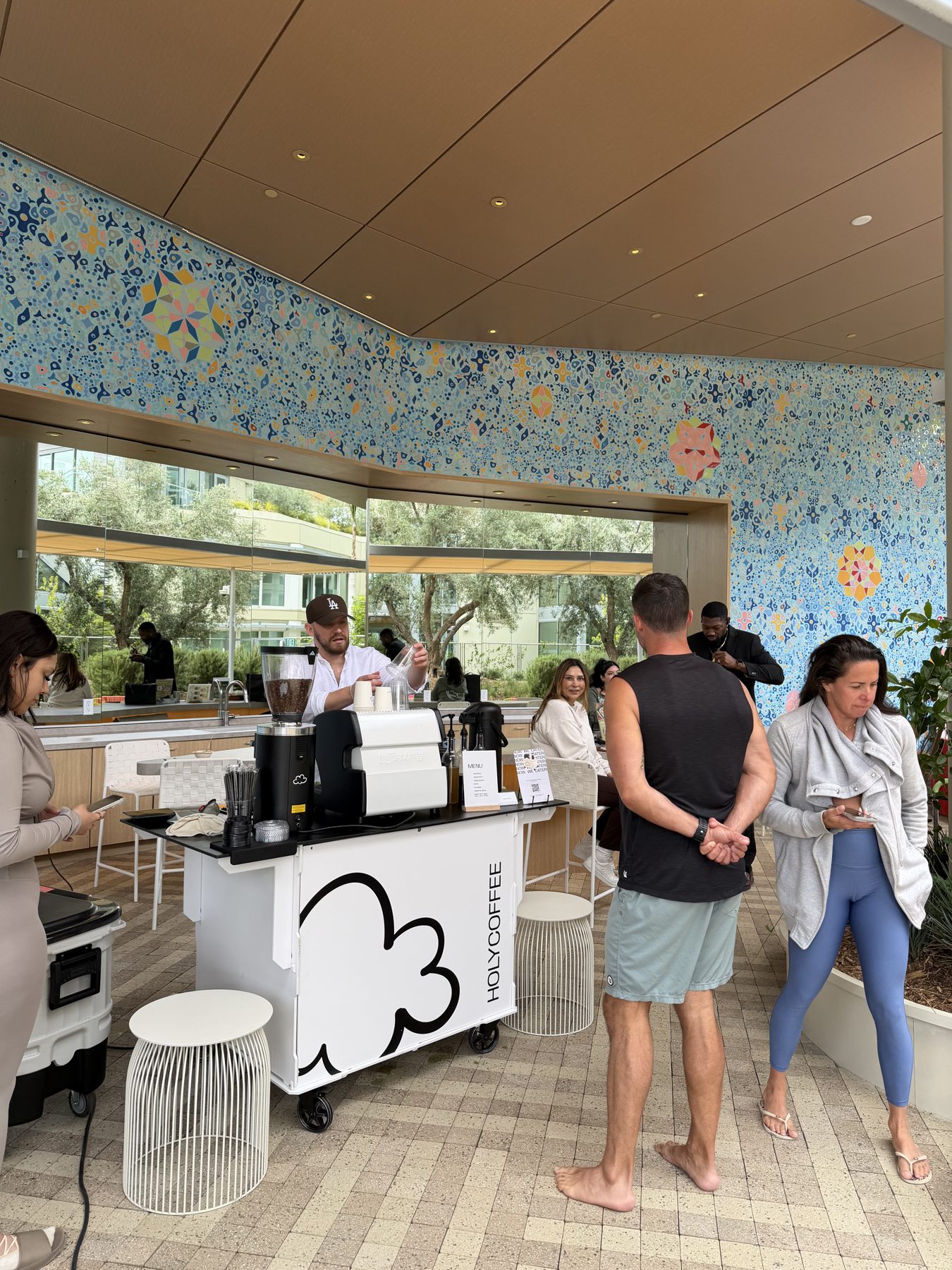 Guests ordering coffee from the Holy Coffee cart on a mosaic pool deck