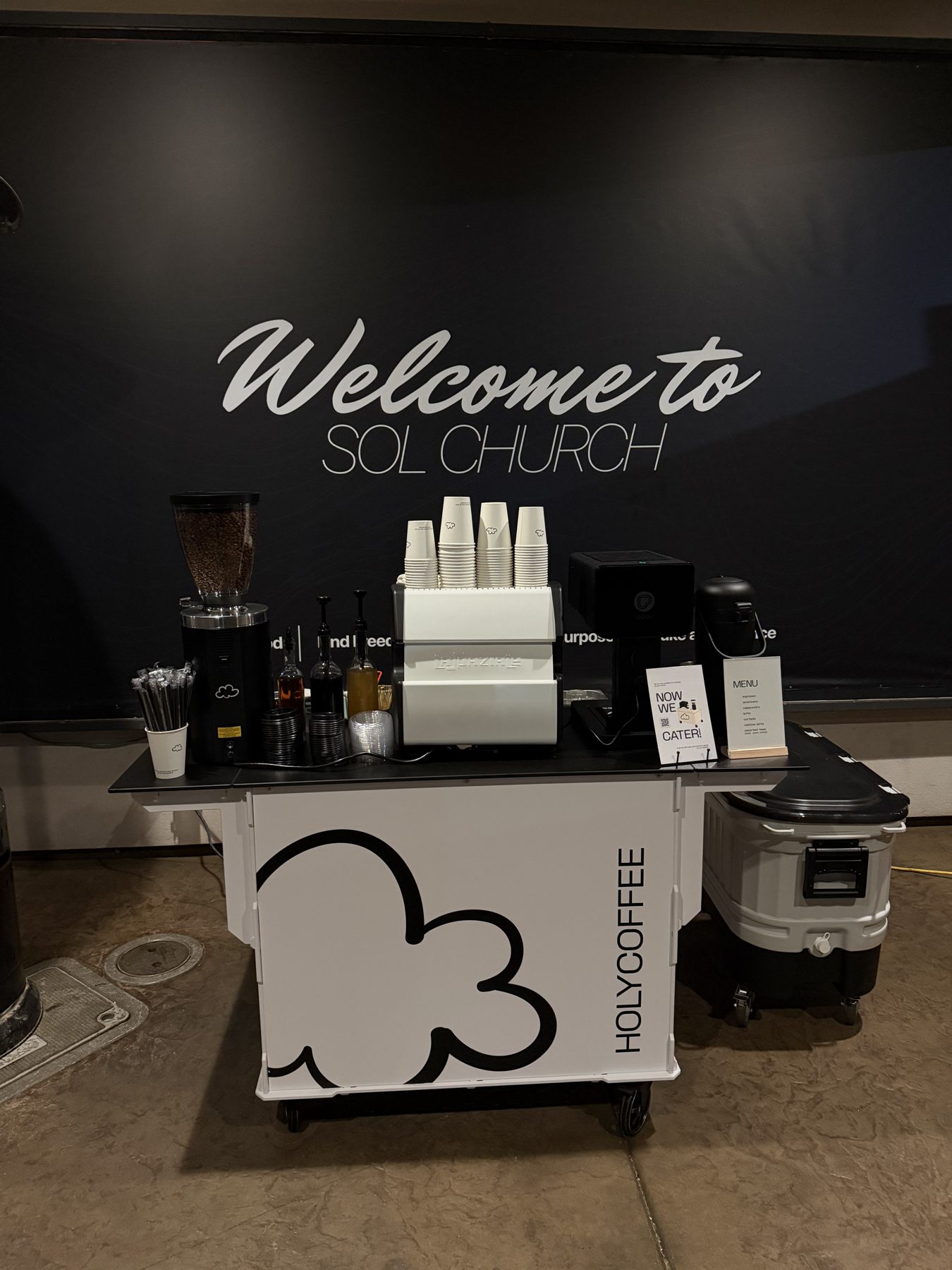 Holy Coffee cart at Sol Church in front of the welcome wall