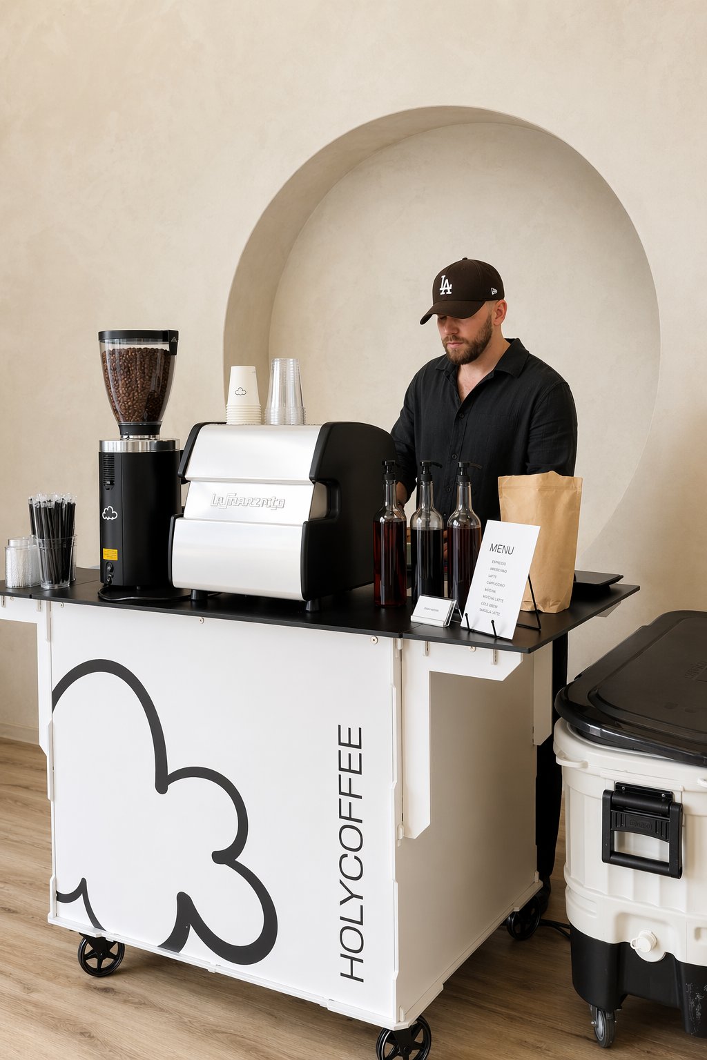 Barista at the Holy Coffee cart in a cream venue with an arched alcove