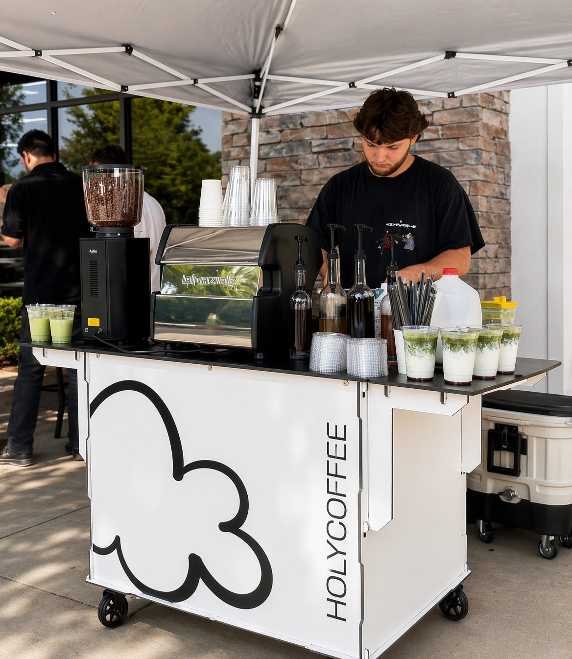 Barista pulling espresso at the Holy Coffee cart under a white event tent