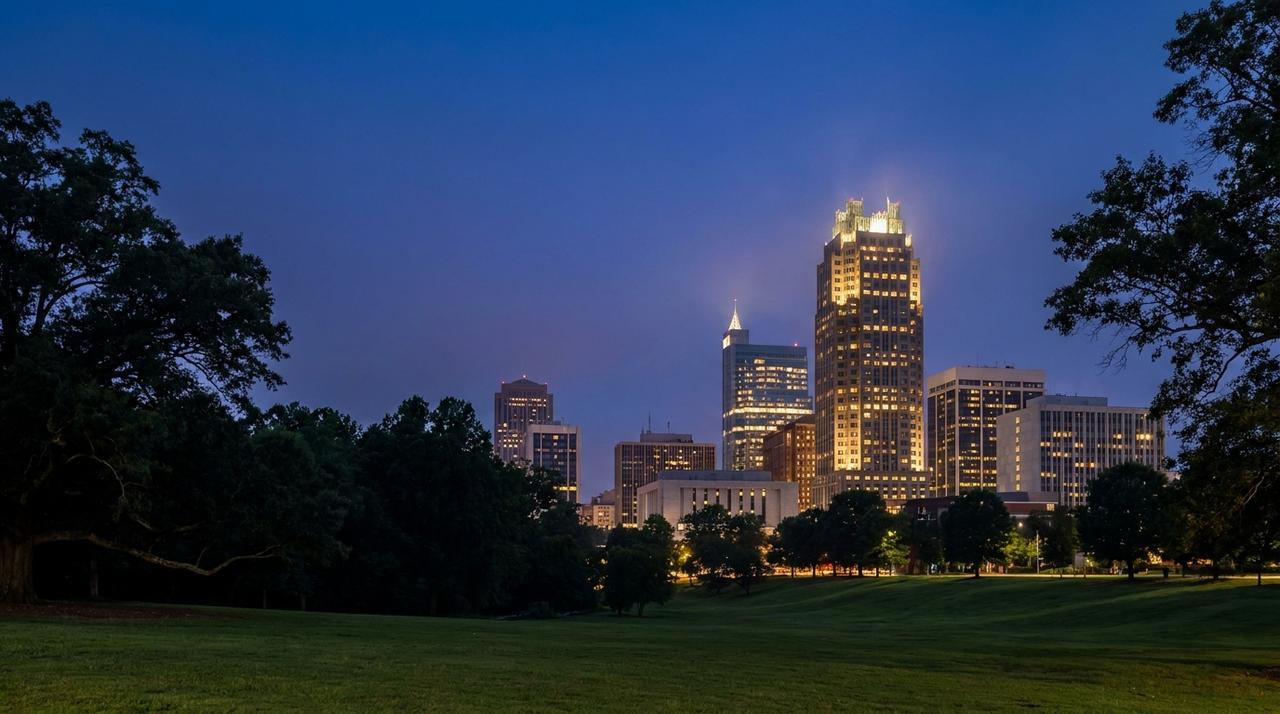 The downtown Raleigh skyline at blue hour seen across the lawn at Dix Park