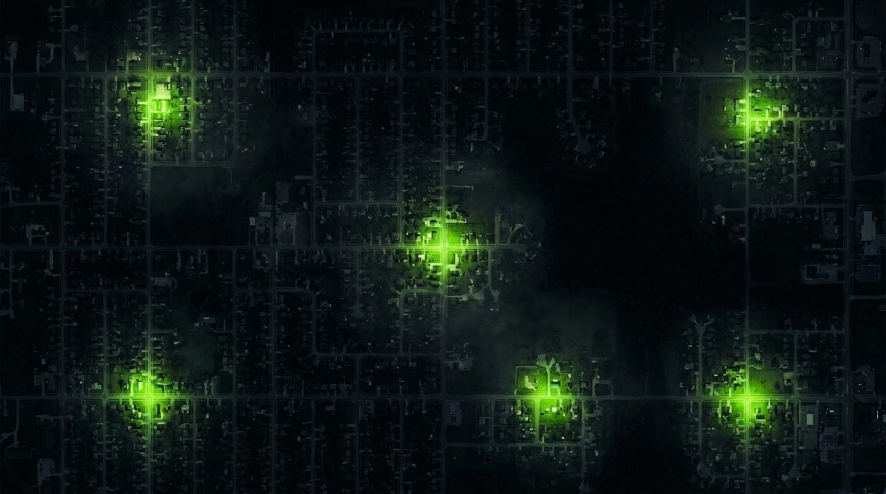 Top down night view of a wide suburban area, mostly in darkness, with several small separate pools of green light scattered across it, each holding one small patch