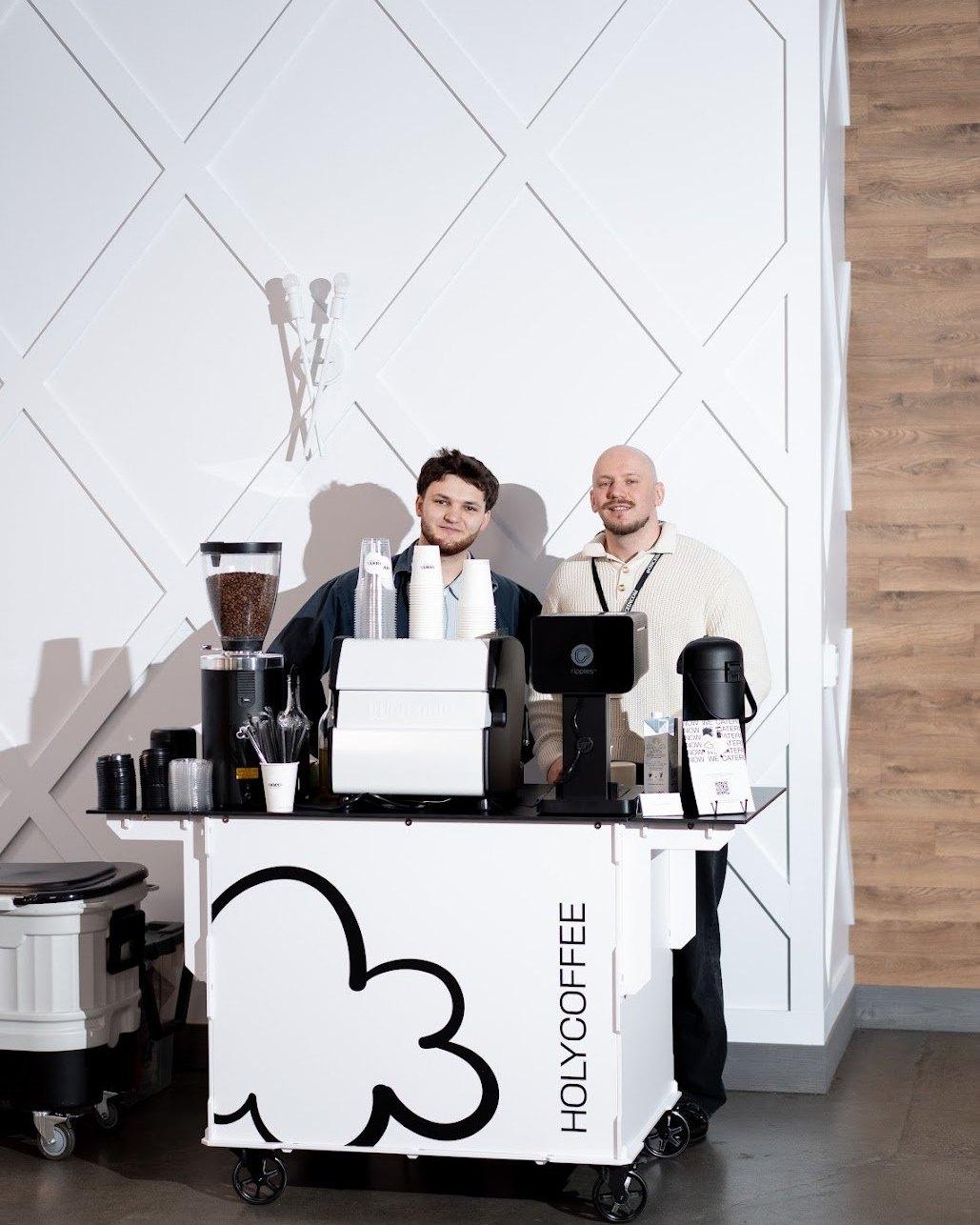 Two Holy Coffee Cart baristas behind the cart at an indoor event