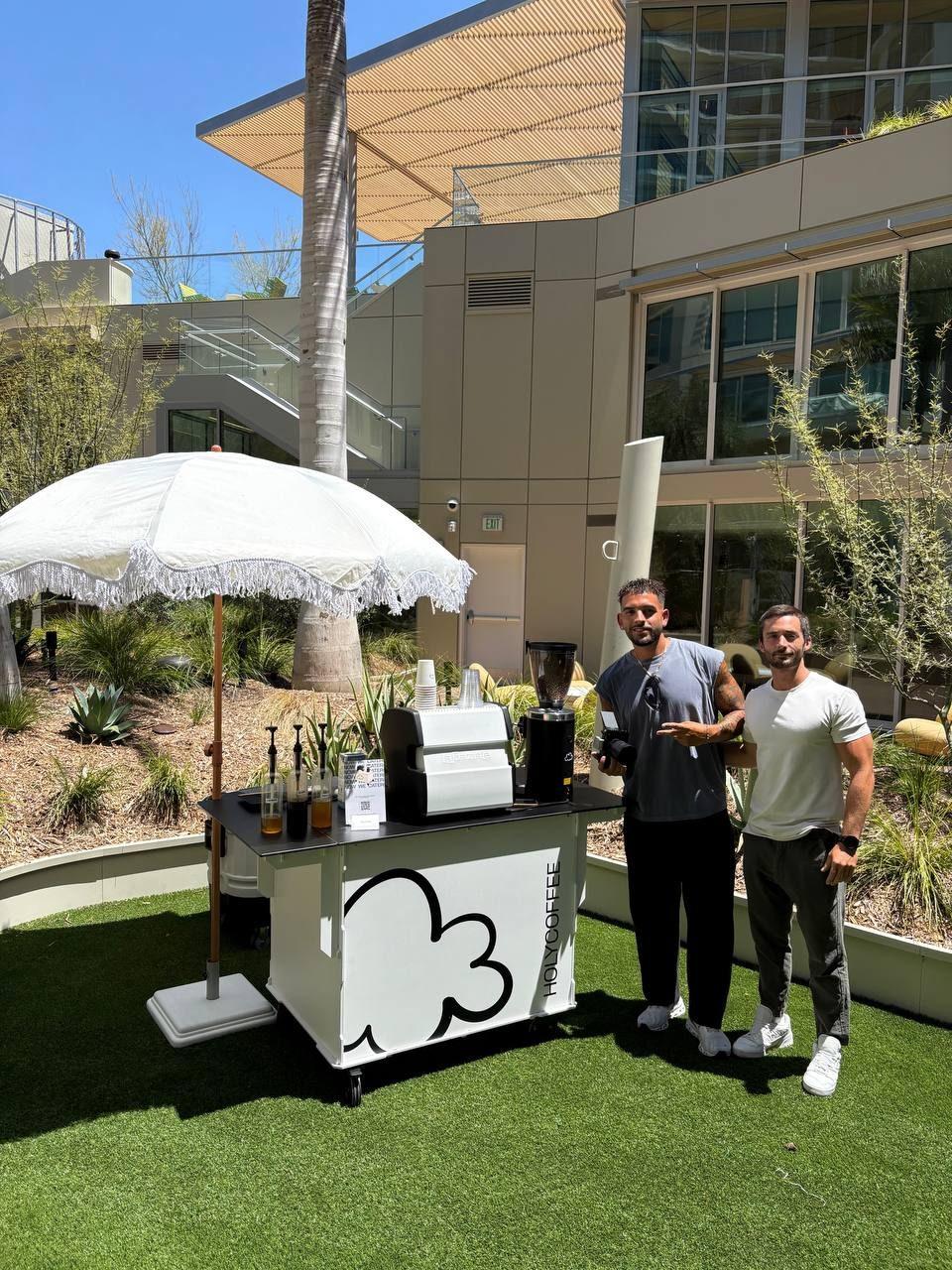 Holy Coffee team beside the cart in a sunny office courtyard